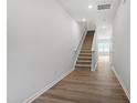 Bright hallway with beautiful floors leading to stairs with carpet and a sunlit room at 127 Central Townes Way # 303, Raleigh, NC 27603
