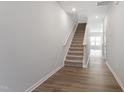 Bright hallway with wood-look flooring, a staircase, and crisp white walls at 131 Central Townes Way # 304, Raleigh, NC 27603