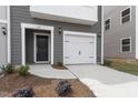 Close-up of a two-story townhouse with a white garage door and a black front door at 139 Central Townes Way # 306, Raleigh, NC 27603