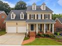 Inviting two-story home with a spacious two-car garage, a brick walkway and a cozy front porch at 1412 Kings Lassiter Way, Raleigh, NC 27614