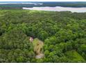 Expansive aerial view of a home nestled in a lush forest with a serene lake backdrop at 145 Ryan Rd, Pittsboro, NC 27312