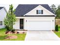 Charming home featuring a dark front door, white siding, a garage, and a newly planted tree at 173 Little Creek Dr, Lillington, NC 27546