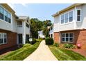 Exterior view of walkway between condo buildings with brick accents and meticulously maintained landscaping at 1911 Falls Landing Dr # 103, Raleigh, NC 27614