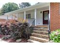 Inviting front porch with stone steps, decorative door, and neatly trimmed landscaping at 325 Northfield Dr, Raleigh, NC 27609