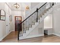 Elegant entryway featuring wood floors, stairs with ornate wrought iron railing, and decorative lighting at 425 Hidden Cellars Dr, Holly Springs, NC 27540