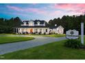 A two-story white home at dusk, featuring a charming wrap-around porch and a large lot at 4737 Uzzle Rd, Rougemont, NC 27572