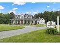 A beautiful two-story white home with charming porch and a 'Thistlewood' sign, set on a large lot at 4737 Uzzle Rd, Rougemont, NC 27572