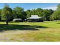 Large, open backyard featuring mature trees and outbuildings, perfect for outdoor activities and storage at 526 Bob Rainey Trl, Burlington, NC 27217