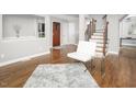 Bright living room with wood floors, a modern white chair, and staircase with wooden handrail at 123 Becket Bend Bnd, Pittsboro, NC 27312