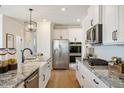 Bright, modern kitchen features white cabinets, granite countertops, and stainless steel appliances at 1305 Westerland Way # 17, Durham, NC 27703