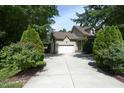 Long driveway leading to a two-car garage, accented by lush greenery at 150 Churchill Rd, Louisburg, NC 27549