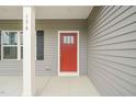 Close-up of a vibrant red front door, featuring a multi-pane window and a sleek, modern design at 156 Harmony Trl, Broadway, NC 27505