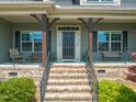 Inviting front porch with a charming entrance featuring decorative pillars, brick stairs, and wrought iron railings at 216 Tarkenton Ct, Clayton, NC 27527