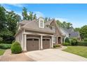 Side view of a two-story home featuring a two-car garage, stone accents, and a well-maintained lawn at 224 Midden Way, Holly Springs, NC 27540