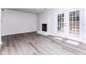 Bright living room featuring sleek floors, a cozy fireplace, and French doors to the backyard at 404 Shannonford Ct, Wake Forest, NC 27587