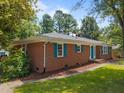 Side view of a brick home featuring well-maintained landscaping, and attractive blue shutters at 722 Baker St, Oxford, NC 27565