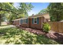 Side view of a brick home featuring well-maintained landscaping, a wooden fence, and attractive blue shutters at 722 Baker St, Oxford, NC 27565