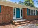 Close-up of the brick home showcasing a vibrant blue front door with sidelights and a brick-stepped entrance at 722 Baker St, Oxford, NC 27565