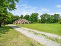 View of home and gravel driveway with a sprawling green lawn leading to a secluded and private property at 8917 Thompson Mill Rd, Wake Forest, NC 27587