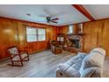 Cozy living room features wood paneling, brick fireplace, ceiling fan, and plush sofa at 9455 Boston Rd, Roxboro, NC 27574