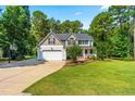 Well-maintained two-story home with an attached garage, long driveway, lush lawn, and mature trees adding to its curb appeal at 1054 Contender Dr, Clayton, NC 27520