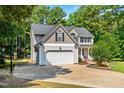 Two-story home featuring an attached garage, long driveway and mature trees providing shade and enhancing the property's setting at 1054 Contender Dr, Clayton, NC 27520