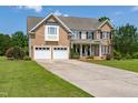Charming brick home featuring a two-car garage, covered front porch and lush green lawn at 109 Lake Point Dr, Clayton, NC 27527