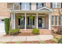 Inviting covered front porch with seating, decorative plants, and charming front door at 109 Lake Point Dr, Clayton, NC 27527