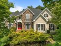 Charming stone and siding home featuring a bright red front door and lush, mature landscaping at 109 San Juan Dr, Chapel Hill, NC 27514