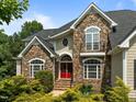 Beautiful stone and siding home featuring a bright red front door and manicured landscaping at 109 San Juan Dr, Chapel Hill, NC 27514