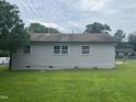 Rear view of a single-story house featuring light siding and green grass at 1851 S Clearview Dr, Henderson, NC 27536