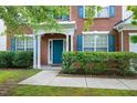 A close up of the brick home's entryway, showcasing the covered porch, front door, and trimmed hedges at 201 Masterwood Way, Morrisville, NC 27560