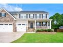 Charming two-story home featuring a cozy front porch swing, a manicured lawn, and a convenient two-car garage at 232 Randleman Ct, Holly Springs, NC 27540