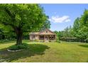 A picturesque front exterior view with a brick facade, a quaint front porch, and a lush, sprawling green lawn at 3315 Mebane Oaks Rd, Mebane, NC 27302