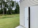 View of a building with white siding and double doors leading to an open, grassy area surrounded by trees at 656 Barneswyck Dr, Fuquay Varina, NC 27526