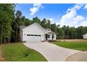 New construction home with a two-car garage and long concrete driveway in a wooded setting at 80 Birchtop Cir, Zebulon, NC 27597