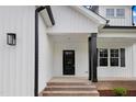 Close-up of a home's front door with black door and pillars, white siding, and brick stairs at 80 Birchtop Cir, Zebulon, NC 27597