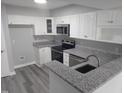 Modern kitchen featuring white cabinets, granite countertops, stainless steel appliances, and gray flooring at 911 Washington St # 102, Raleigh, NC 27605