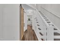Hallway with hardwood floors, staircase, barn door to bathroom, and entryway to the kitchen at 100 Windvale Ct, Cary, NC 27518