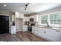 Well-lit kitchen featuring white cabinets, granite countertops, stainless steel appliances, and wood-look floors at 1067 Thompson Rd, Four Oaks, NC 27524