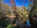 Scenic pond reflecting colorful autumn foliage, creating a tranquil and picturesque natural landscape on a sunny day at 126 Mildred Place, Broadway, NC 27505