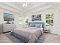 Calm main bedroom featuring a tray ceiling, a plush bed, and ample natural light from three windows at 1613 Patterson Grove Rd, Apex, NC 27502