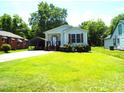 Cozy single-story home with light siding, a welcoming front porch, and a large lawn at 220 Howard St, Burlington, NC 27217
