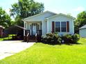 Quaint single-story home featuring light siding, a cozy front porch, and convenient covered parking at 220 Howard St, Burlington, NC 27217