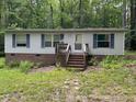 Single story home with brick foundation, light siding, blue shutters, and a small porch nestled in a wooded area at 3539 Charlies Ct, Wake Forest, NC 27587