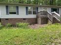 Single story home with brick foundation, light siding, blue shutters, and a small porch nestled in a wooded area at 3539 Charlies Ct, Wake Forest, NC 27587