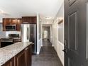 View of kitchen with stainless appliances, dark wood cabinets, and granite countertops from entryway at 102 Sanair Ct, Apex, NC 27502