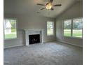 Bright living room featuring plush carpeting, a cozy fireplace, and abundant natural light from three large windows at 175 Oakfield Trace Dr, Four Oaks, NC 27524