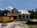 New home under construction with protective wrap against a blue sky surrounded by pine trees at 214 Pretty Run Branch Ln, Wendell, NC 27591