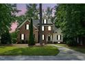 Charming two-story brick home with a manicured lawn, mature trees, and a welcoming front entrance at dusk at 3020 Woods Walk Way, Rocky Mount, NC 27804